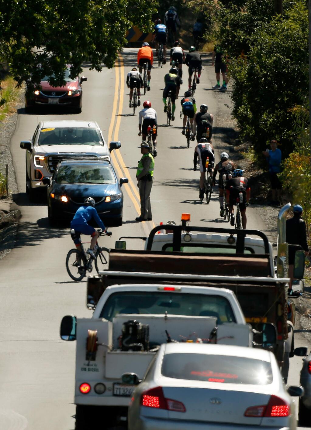 Motorists wait as triathletes turn onto Faught Road from Chalk Hill Road during the cycling stage of Ironman Santa Rosa in Windsor, California, on Saturday, May 11, 2019. (ALVIN JORNADA/ PD)