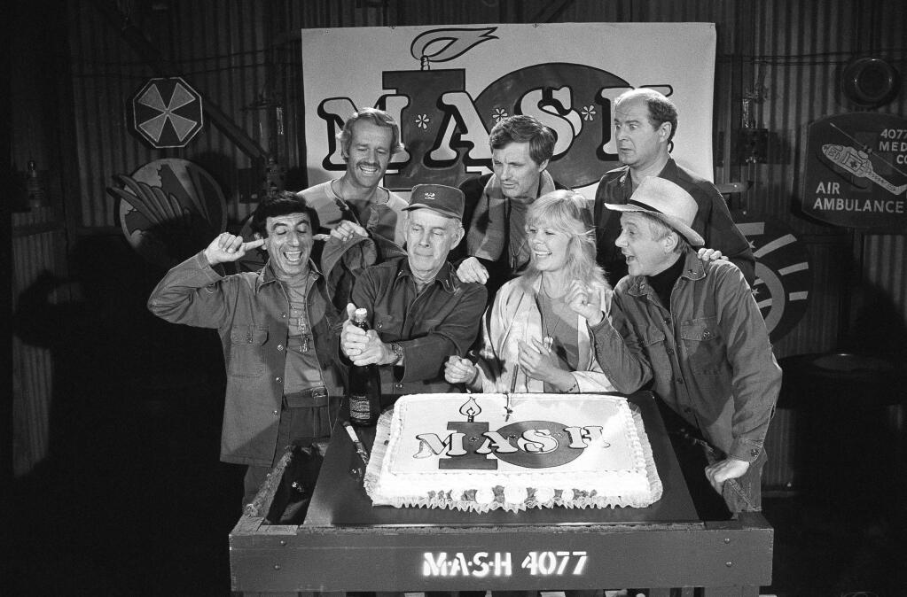 FILE - In this Oct. 22, 1981, file photo, Jamie Farr, from front left, plugs his ears as cast members of the 'M.A.S.H.' television series cast Harry Morgan, Loretta Swit, William Christopher and, from back from left, Mike Farrell, Alan Alda and David Ogden Stiers celebrate during a party on the set of the popular CBS program in Los Angeles. Stiers a prolific actor best known for playing a surgeon on the television series 'M.A.S.H.' has died, the actor's agent Mitchell Stubbs confirmed Saturday night, March 4, 2018, in an email. He was 75. (AP Photo/Huynh, File)
