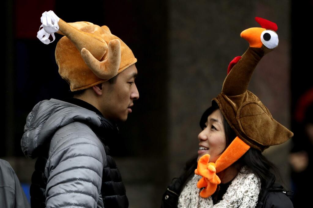 Tamari Hedani, right, and her boyfriend, Chris Chu, both from San Francisco, wear turkey hats prior to the start of the Macy's Thanksgiving Day Parade, Thursday, Nov. 27, 2014, in New York. (AP Photo/Julio Cortez)