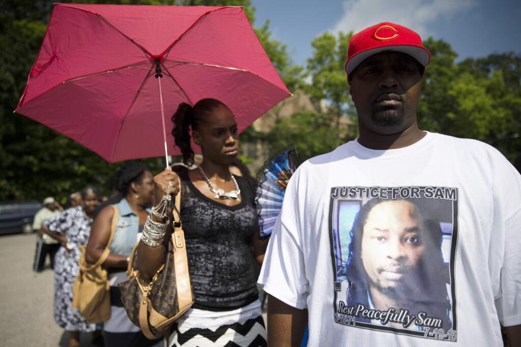 Mourner Bill Smith wears a shirt bearing the likeness of Samuel DuBose as he waits on line outside funeral services for Dubose at the Church of the Living God in the Avondale neighborhood of Cincinnati, Tuesday, July 28, 2015. Dubose was fatally shot by a University of Cincinnati police officer who stopped him for a missing license plate. (AP Photo/John Minchillo)