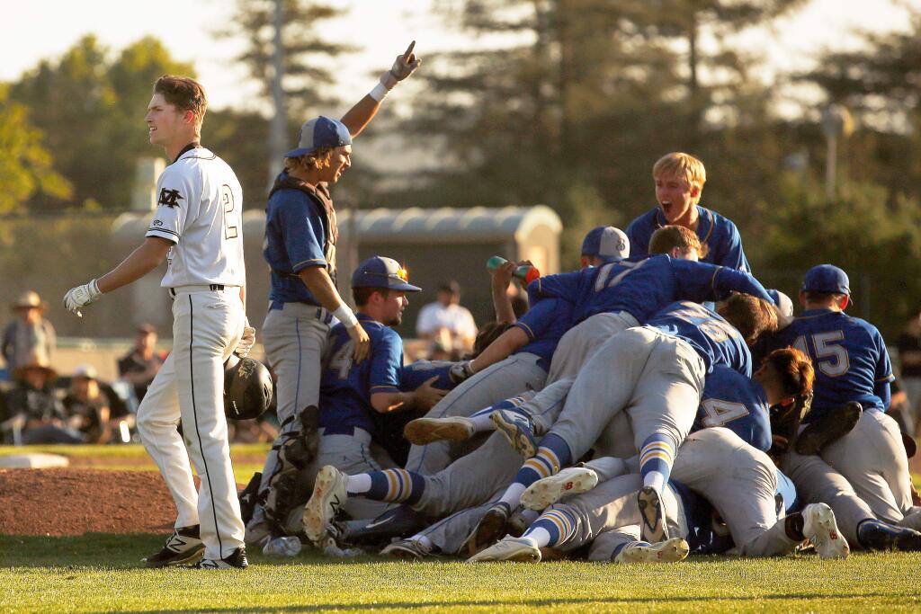 Maria Carrillo's Bryce Veler, left, walks back to the dugout past a dogpile of celebrating Benicia Panthers after they defeated the Pumas 6-2 in the NCS Division 2 baseball championship game between Benicia and Maria Carrillo high schools in Santa Rosa, California, on Wednesday, May 29, 2019. (Alvin Jornada / The Press Democrat)