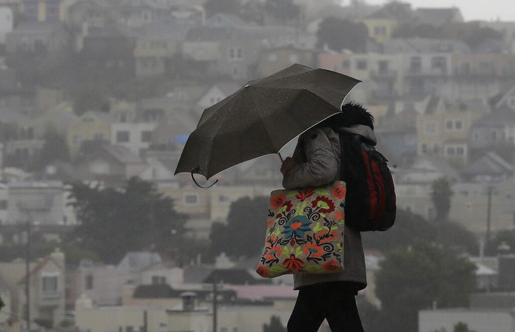 A woman carries an umbrella as she crosses a street in San Francisco, Tuesday, Feb. 7, 2017. Flash flood watches are in place for parts of Northern California down through the Central Coast as heavy rains swamp roads and threaten to overtop rivers and creeks. (AP Photo/Jeff Chiu)