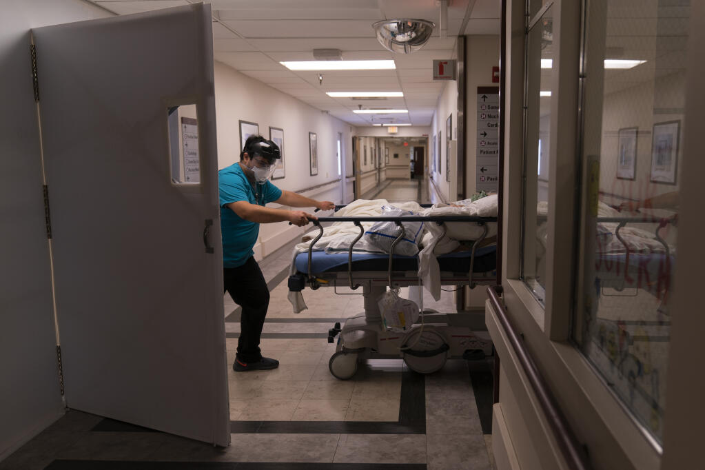 FILE - In this Feb. 19, 2021, file photo, medical transporter Adrian Parrilla moves a patient into a COVID-19 unit at Mission Hospital in Mission Viejo, Calif. (AP Photo/Jae C. Hong, File)