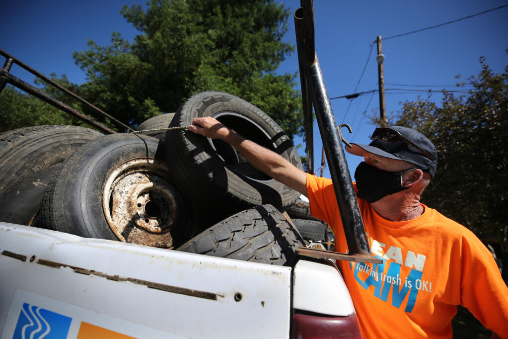 Chris Brokate, founder and executive director of Clean River Alliance, unloads abandoned tires that he collected in his truck in Guerneville on Aug. 6, 2020. (Beth Schlanker/ The Press Democrat)