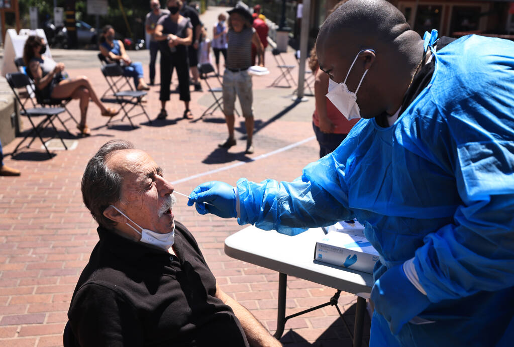 Tony Madrid, who has been vaccinated, receives a COVID-19 quick test by Charles Everett of Stockton, Friday, July 30, 2021, at a county pop-up testing and vaccination clinic in Guerneville.  (Kent Porter / The Press Democrat) 2021