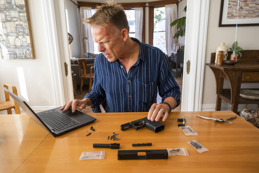 Press Democrat writer Austin Murphy checks a how-to video on YouTube as he builds a Polymer80 Glock 19 clone "ghost gun" with parts acquired through internet dealers in his home on Thursday, Oct. 14, 2021. (John Burgess / The Press Democrat)