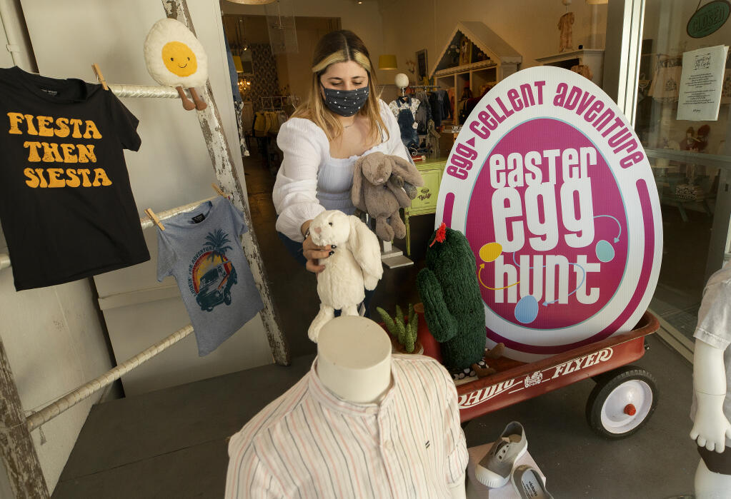 Matillda Prole adds stuffed bunnies to the window display at Cupcake on 4th Street in Santa Rosa on Tuesday, March 16, 2021.  Downtown Santa Rosa businesses are hoping to drum up some business with an Easter "Egg" Hunt where kids can collect stickers from businesses and turn them in for prizes.    (John Burgess / The Press Democrat)