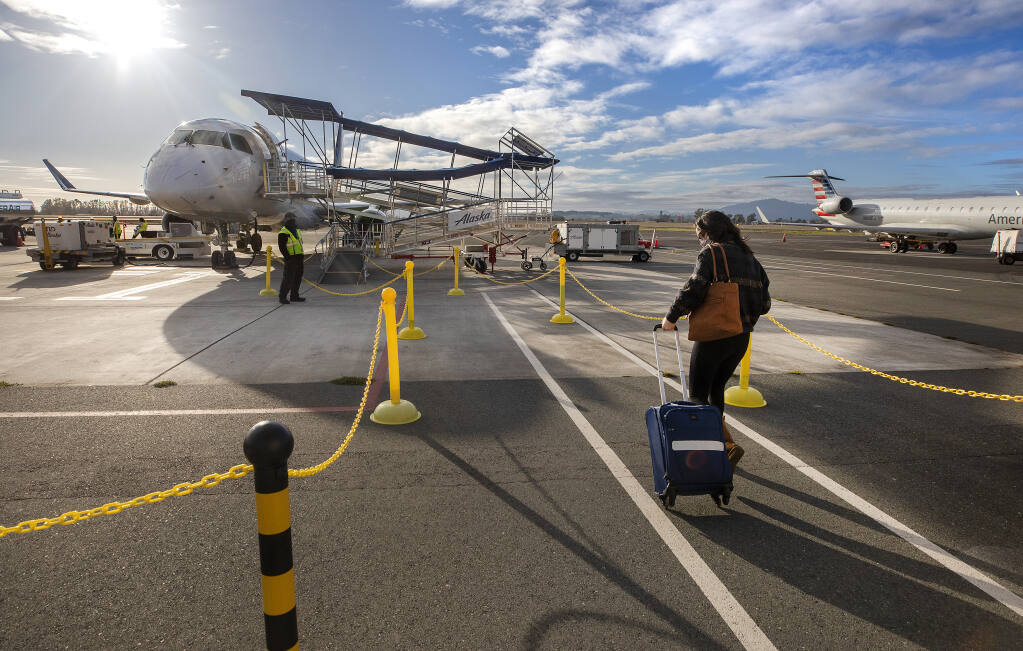 One of only six passengers makes their way to board an Alaska Airlines flight to Santa Ana at Charles M. Schulz-Sonoma County Airport on Tuesday, Dec. 15, 2020.  (John Burgess / The Press Democrat)