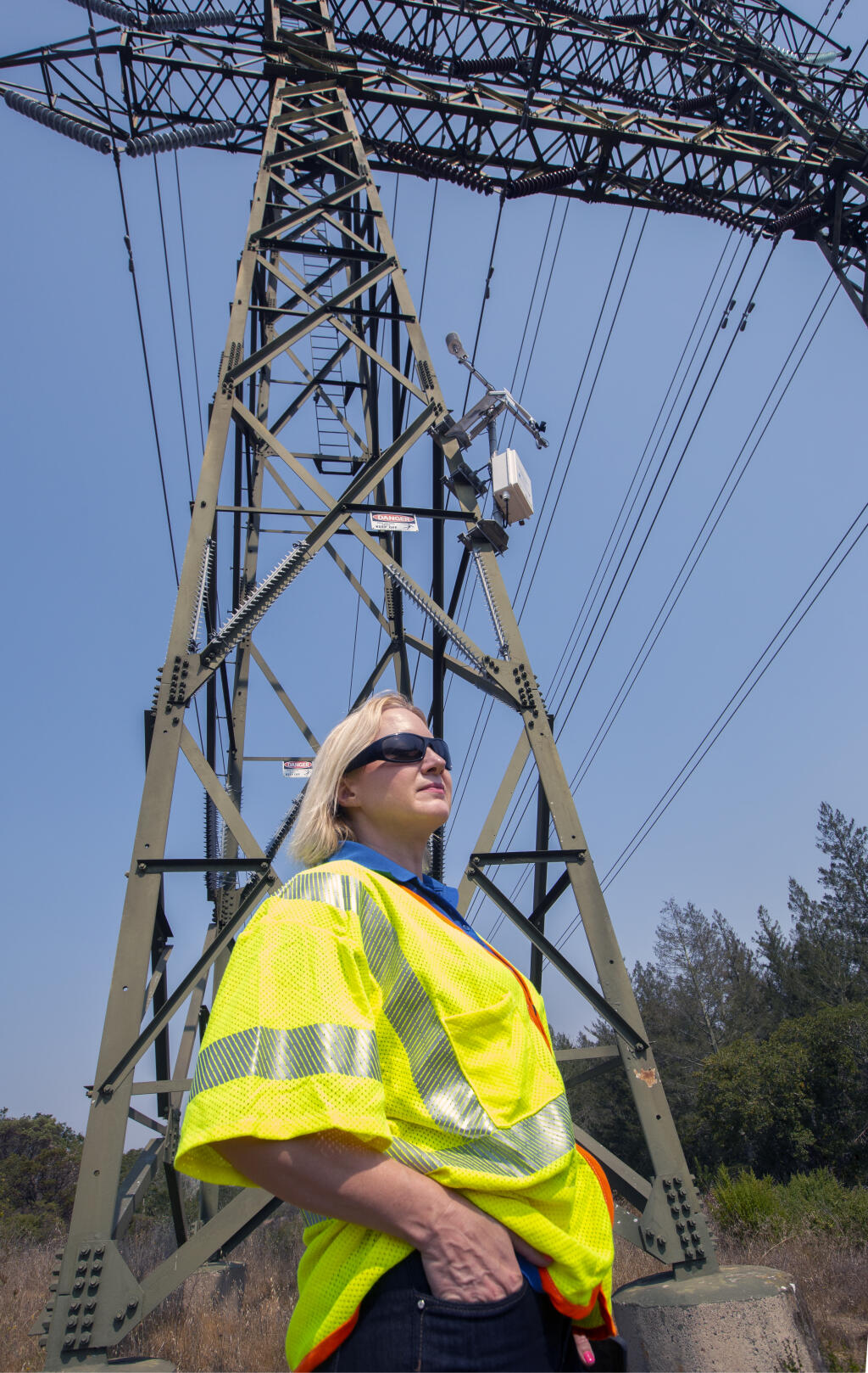 Deanna Contreras, PG&E media rep, stands below a weather station attached to power lines at the top of a hill in the Oakmont community on Highway 12, on Friday, Aug. 27, 2021. (Photo by Robbi Pengelly/Index-Tribune)