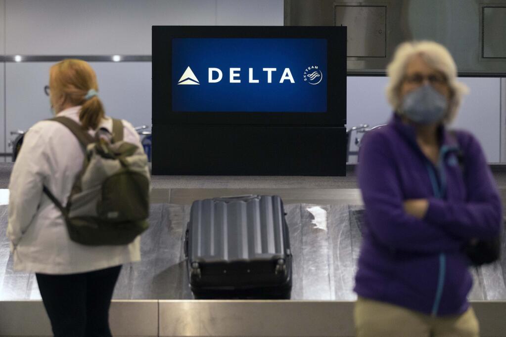 Passengers wait for luggage in the arrival area of Delta Air Lines, Monday, July 12, 2021, at Logan International Airport in Boston.  (AP Photo/Michael Dwyer)