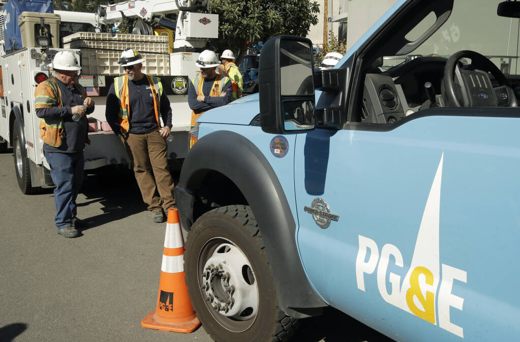 FILE - Pacific Gas & Electric and CalTrans workers stand near the Caldecott Tunnel on during power cuts Oct. 9, 2019, in Oakland, Calif. (AP Photo/Ben Margot, File)