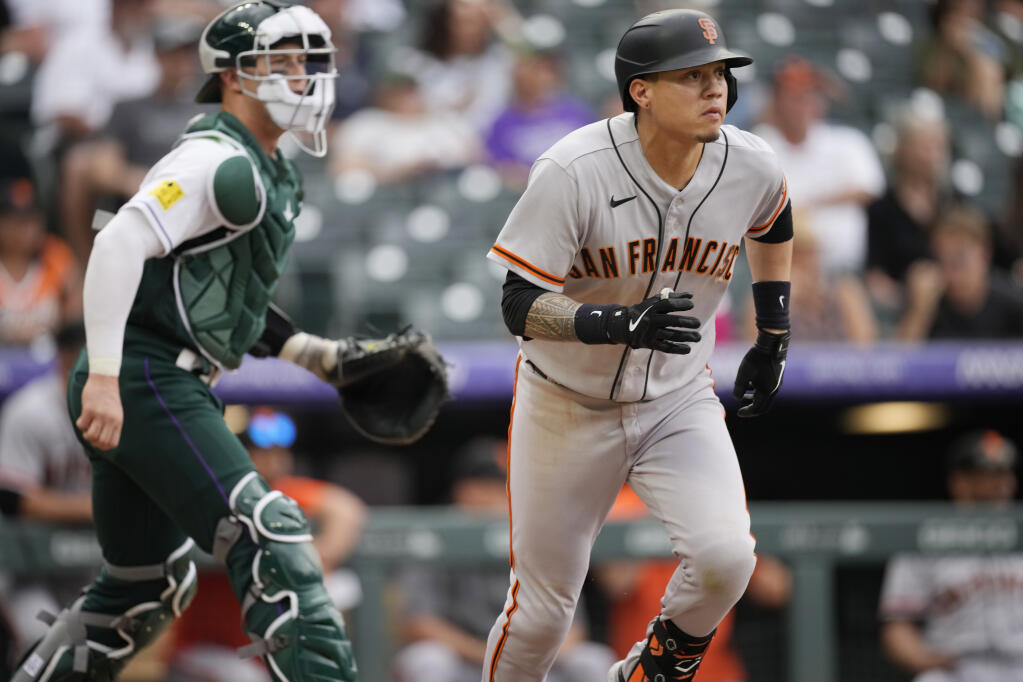 San Francisco Giants' Wilmer Flores, right, and Colorado Rockies catcher Brian Serven follow the flight of Flores' sacrifice fly to drive in the go-ahead run in the 11th inning of a baseball game Sunday, Aug. 21, 2022, in Denver. (AP Photo/David Zalubowski)