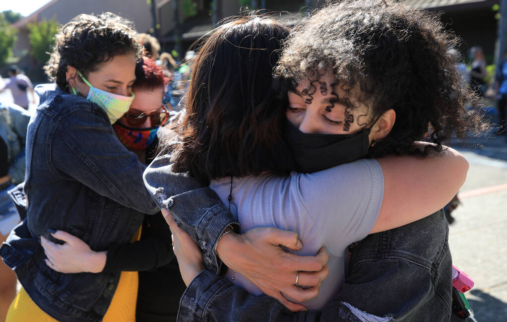 Kristen Aumoithe, left, and Amber Lucas are embraced by friends, Saturday, May 22, 2021 at the end of a poetry reading rally in front of the Santa Rosa Police Department. The two, along with Rowan Dalbey, have been accused of felony vandalism and conspiracy for smearing pig's blood on the former home of retired police officer Barry Brodd,  a police expert who testified on behalf of fired Minneapolis police officer Derek Chauvin during his murder trial in the death of George Floyd. (Kent Porter / The Press Democrat) 2021