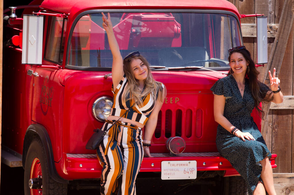 Christina Kruglikov, left, and Olga Shigapova, both of Fremont, Calif., pose for pictures in front of an old fire truck, during the "Wine for a Cause Flight" event to benefit Redwood Empire Food Bank, held at Hook & Ladder Winery in Santa Rosa, Calif., on Saturday, May 22, 2021. (Photo by Darryl Bush / For The Press Democrat)