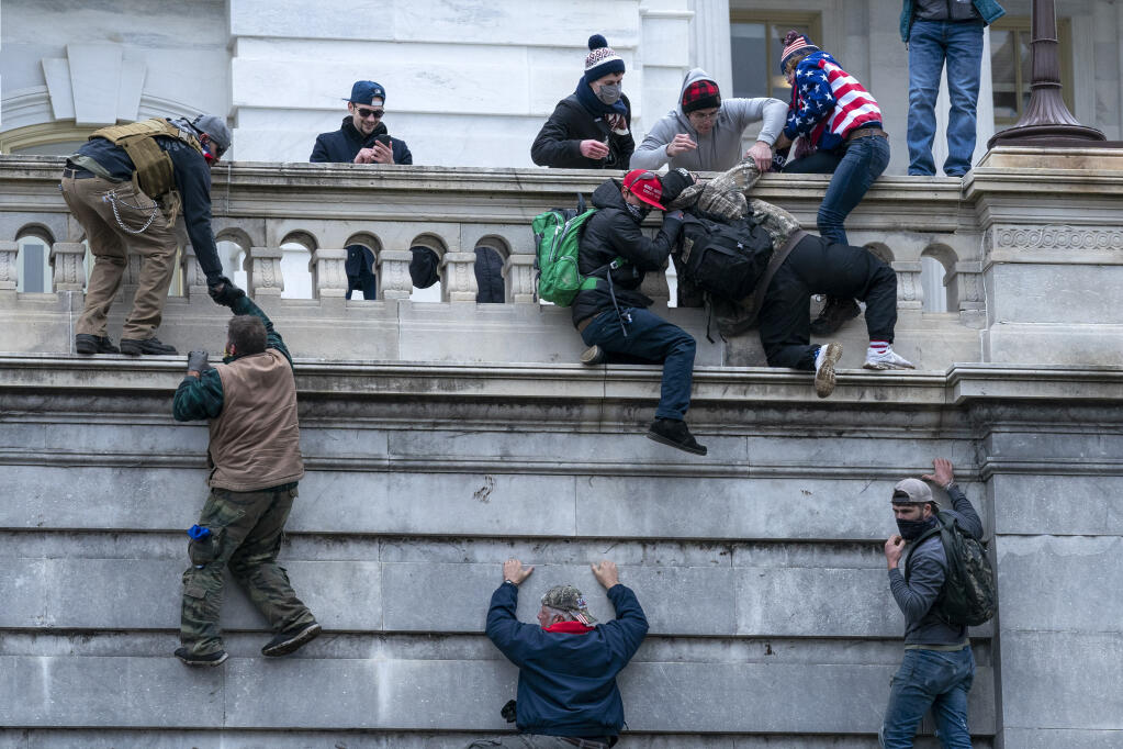 FILE - Rioters loyal to President Donald Trump climb the west wall of the the U.S. Capitol, Jan. 6, 2021, in Washington. (AP Photo/Jose Luis Magana, File)