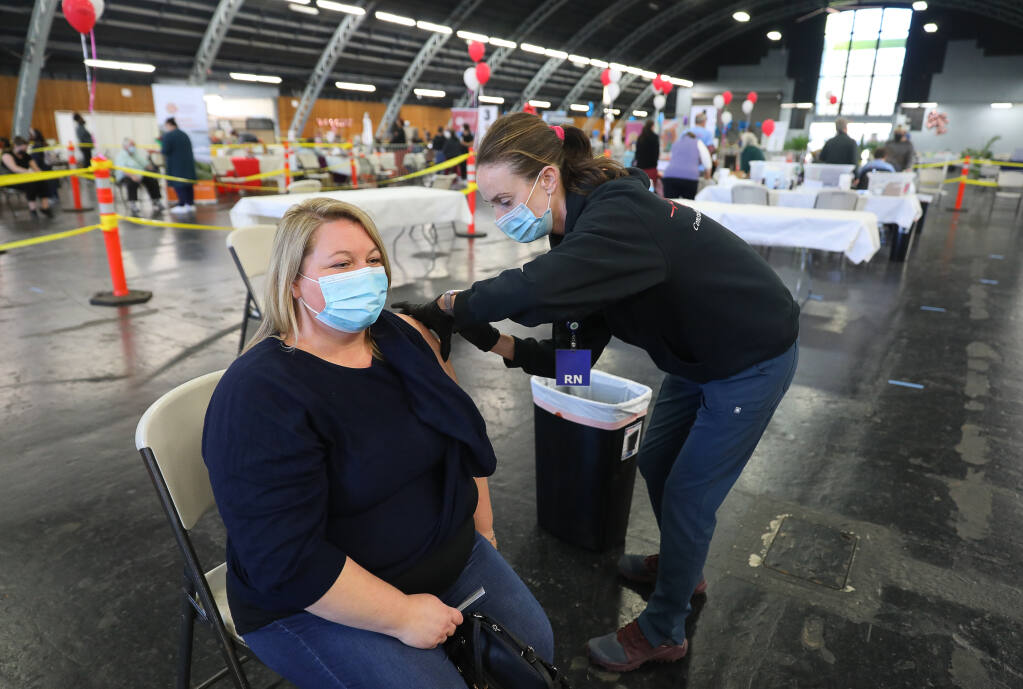 Registered nurse Lilly Briggs, right, administers the Moderna COVID-19 vaccine to Sabrina Nesbit at the DEMA, Disaster Emergency Medical Assistance, vaccination clinic, at the Sonoma County Fairgrounds, in Santa Rosa on Monday, Feb. 22, 2021. (Christopher Chung / The Press Democrat)