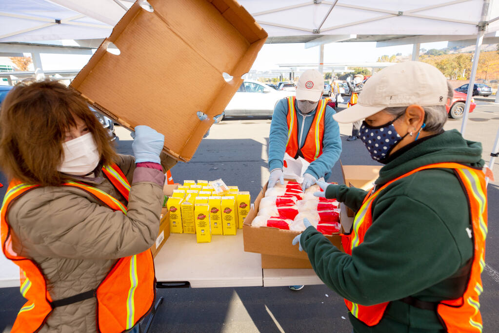 From left: volunteers Kathleen Robarts, Mary Seggerman, and Rachel Elizondo prepare dairy products and meat to be portioned for recipients during a Redwood Empire Food Bank food distribution at Kaiser Permanente in Santa Rosa, California, on Saturday, November 21, 2020. (Alvin A.H. Jornada / The Press Democrat)