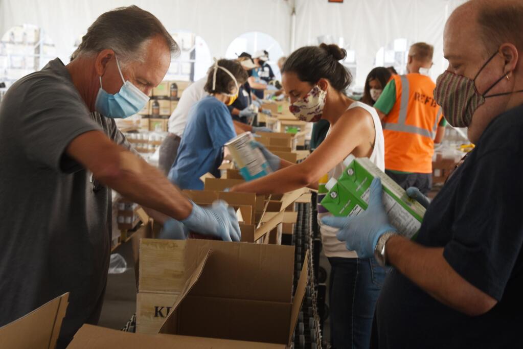 From left, John Sawyer, Rachel Hundley and Chris Hightower were part of a group of elected officials packaging food at Redwood Empire Food Bank in Santa Rosa on Saturday, Aug. 8, 2020. (Erik Castro / for The Press Democrat)