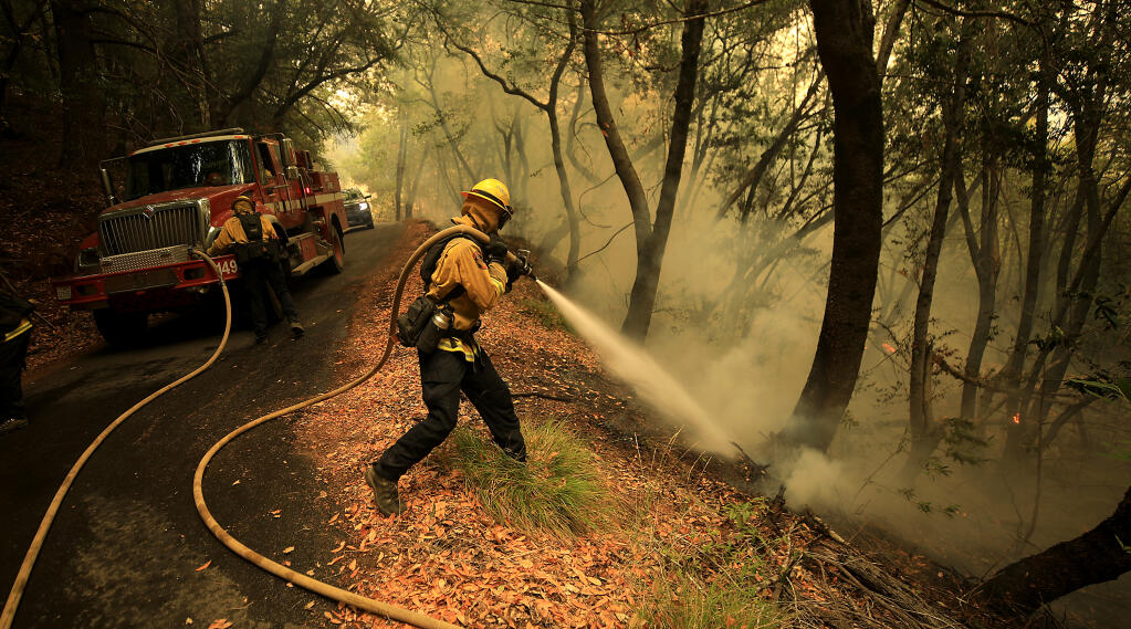 Jackson Baldwin of Cal Fire puts out a spot fire as crews attempt to keep the Walbridge fire from advancing east to Mt. Jackson and dropping in to the Rio Nido area, Wednesday, Aug. 19, 2020.(Kent Porter / The Press Democrat) 2020
