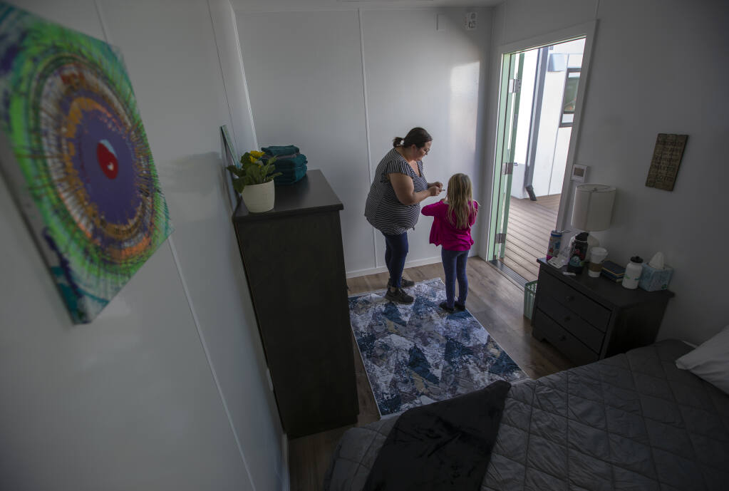 Mom Cortney Bowser works with her daughter Evie, 7, as they decorate a room they adopted at Labath Landing, a 60-unit supportive housing facility in Rohnert Park on Oct. 23, 2022, to prepare for its opening the following day. Monday. Along with Evie’s hand-spun art, the pair provided things like rugs, sheets and towels for the incoming guest. The facility will provide temporary housing to people experiencing homelessness and is expected to serve about 100 people a year. It was paid for through state Project Homekey funds and will be operated by nonprofit HomeFirst.   (Chad Surmick / The Press Democrat)