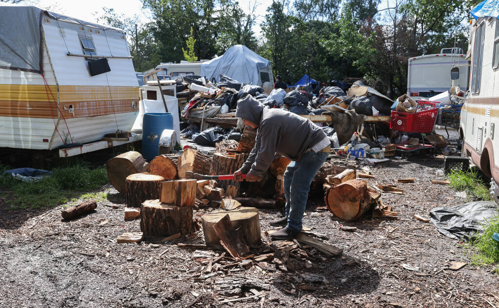 Armando, who declined to provide his last name, chops wood at the homeless camp on a property along Old Stony Point Road in Santa Rosa on Friday, April 22, 2022. (Christopher Chung/ The Press Democrat)