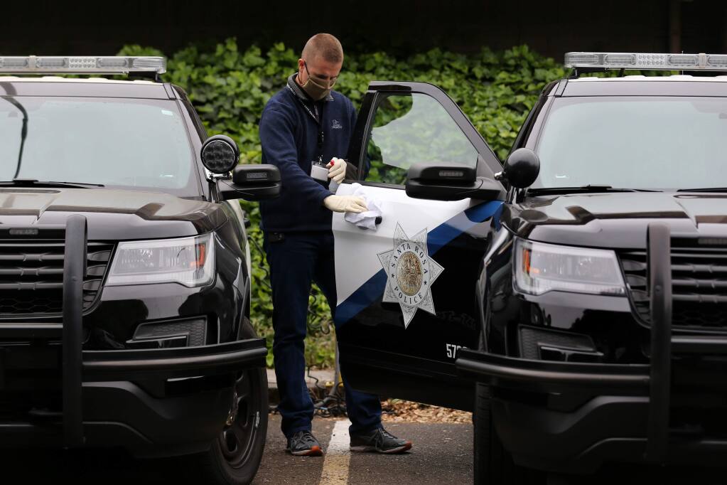 Santa Rosa police officer trainee Rhylind McAuliffe wipes down a patrol car as part of his duties at the Santa Rosa Police Headquarters in Santa Rosa, California on Sunday, May 10, 2020. (BETH SCHLANKER/ The Press Democrat)