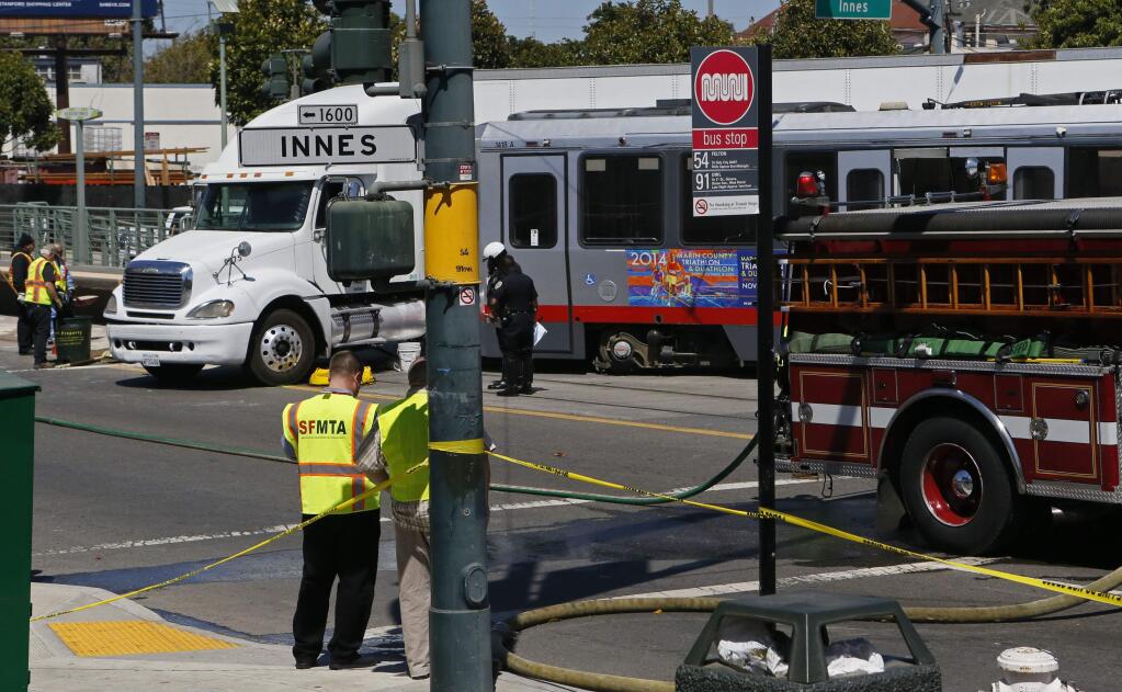 A collision between a big rig truck and a MUNI light rail vehicle at the intersection of Innes and 3rd streets shut down both north and south bound lanes of 3rd street as emergency personnel responded to the scene in San Francisco on Friday Aug. 1, 2014. (AP Photo/San Francisco Chronicle, Michael Macor)