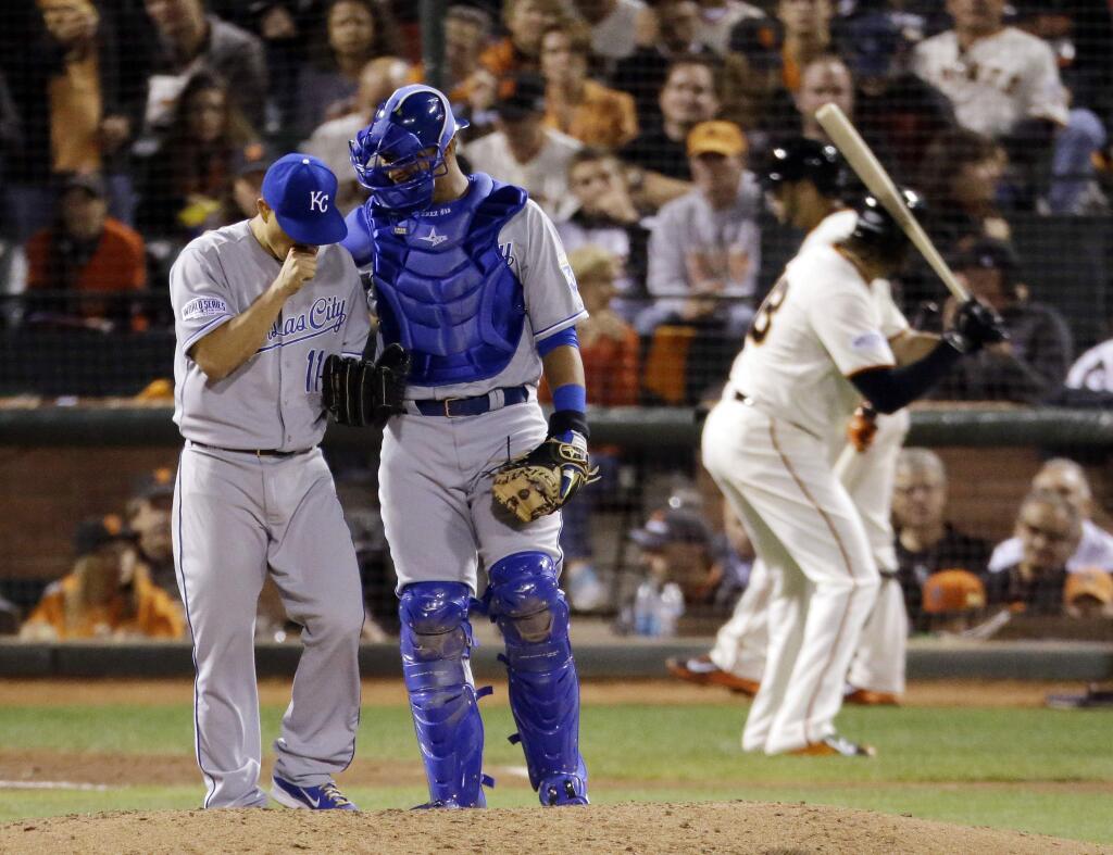 Kansas City Royals Jeremy Guthrie, left, and Salvador Perez confer on the mound as the Giants' Michael Morse waits to bat during the sixth inning of Game 3 of the World Series Friday, Oct. 24, 2014, in San Francisco. (AP Photo/Charlie Riedel)