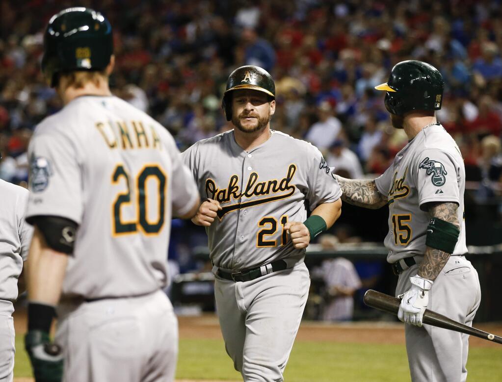 Oakland Athletics' Stephen Vogt (21) is congratulated by Mark Canha (20) and Brett Lawrie (15) after scoring on a two-run single by Josh Reddick against the Texas Rangers during the eighth inning of a game, Friday, May 1, 2015, in Arlington, Texas. The Athletics won 7-5. (AP Photo/Jim Cowsert)