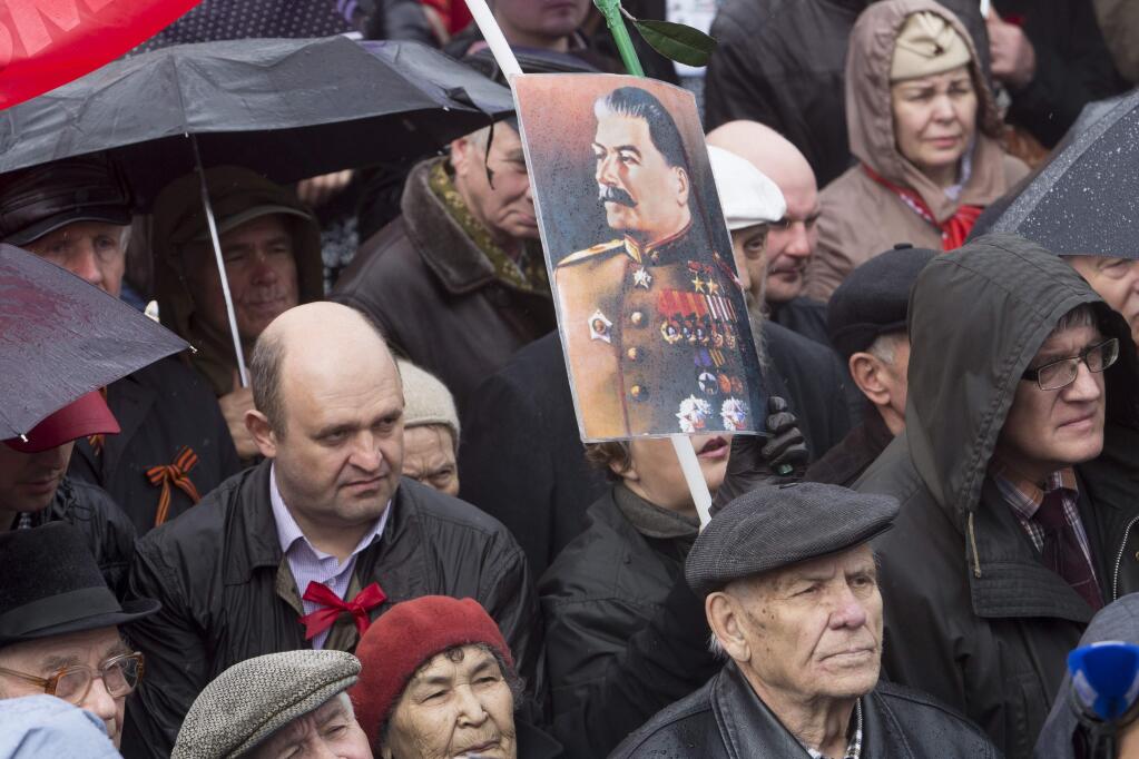 Communists carry a portrait of former Soviet leader Josef Stalin during May Day demonstration in Moscow, Friday, May 1, 2015. As in Soviet times, tens of thousands of cheerful workers paraded across Red Square despite a chilly rain, but instead of red flags with the Communist hammer and sickle, they waved the blue flags of the dominant Kremlin party and the Russian tricolor. Participants, who came in groups organized by their trade unions, said the May 1 parade was a tradition going back to their childhood. (AP Photo/Denis Tyrin)