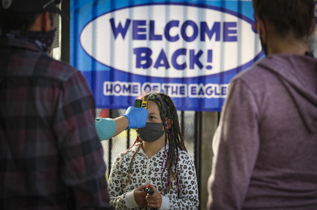 Layla Martinez, 9, a third grader at La Tercera Elementary School, gets her temperature checked before entering campus. Petaluma’s elementary school students returned to hybrid in-person classes on Monday, April 12, 2021. (CRISSY PASCUAL/ARGUS-COURIER STAFF)