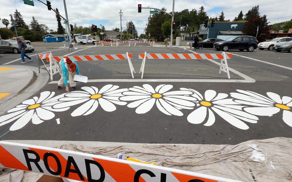Photos by John Burgess / The Press Democrat Artist Karen Macken puts the finishing touches on Shasta daisies stenciled into the crosswalk Tuesday on the corner of Santa Rosa Avenue and Mill Street in Santa Rosa. Local artists are hoping to brighten up an area that residents for years have been pushing the city to clean up.