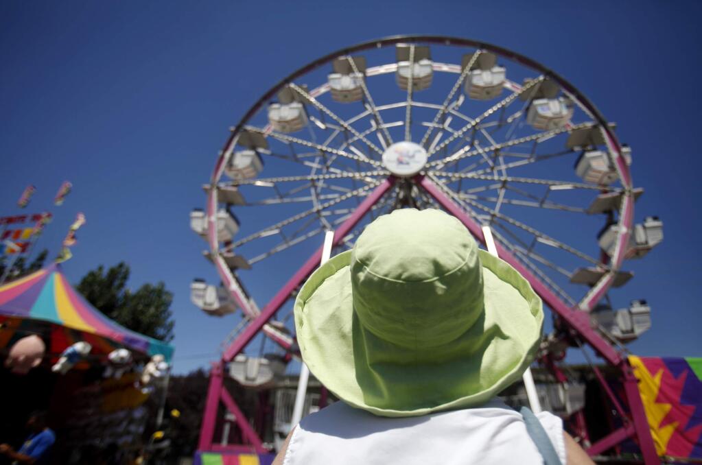 Teresa Purroy looks up and watches as her great grandchildren ride the Ferris wheel at the 2012 Sonoma County Fair in Santa Rosa, California. (BETH SCHLANKER/ The Press Democrat)