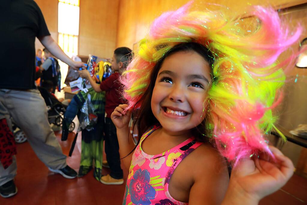 Neveah Benjamin, 4, dazzles her parents in a multi-colored wig at the Santa Rosa Christian Church on Friday. The Santa Rosa Police Department sponsored the Halloween costume drive. (photo by John Burgess/The Press Democrat)