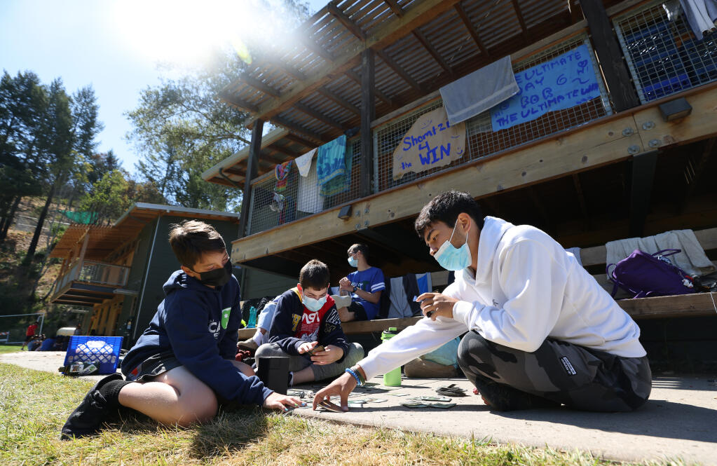 Counselor in training Lucas Goldsobel, right, plays a card game with campers Ben Kreiman and Cameron Weiner at Camp Newman near Santa Rosa on Sunday, July 4, 2021.  (Christopher Chung/ The Press Democrat)