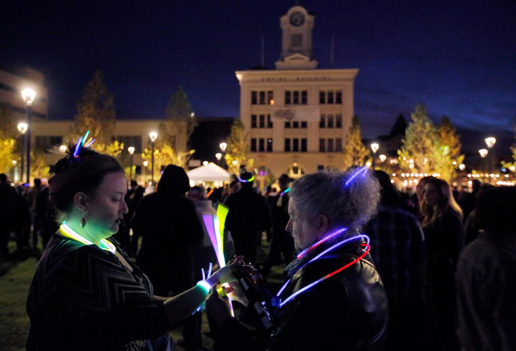 Cheri Askim, left and her mother Corrine Askim, both of Santa Rosa share a bunch of colorful glow sticks during a vigil for the community to come together in the wake of the fires around Sonoma County, at Old Courthouse Square in Santa Rosa, California on Friday, October 20, 2017. (Alvin Jornada / The Press Democrat)