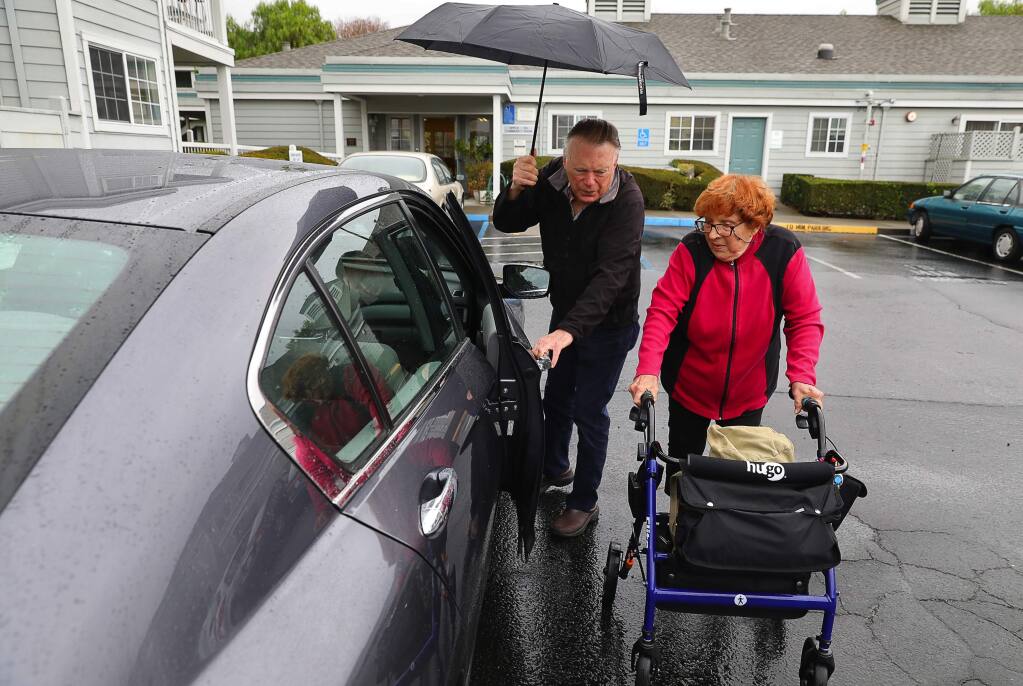 Volunteer iRIDE Petluma driver Jack Rhodes helps passenger Ellie Jaquish to his car, to transport her to City Sports Club in Petaluma on Friday, January 5, 2018. (Christopher Chung/ The Press Democrat)