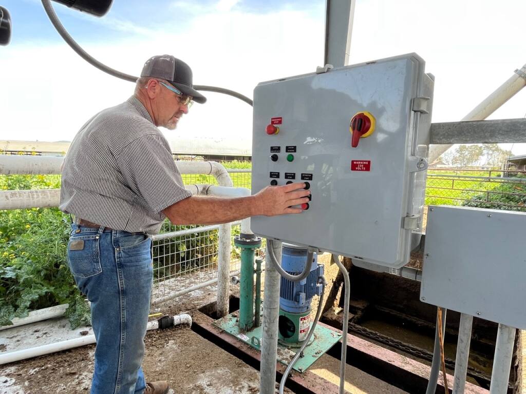 Sonoma County dairy rancher Doug Beretta, shown here on April 3, 2022, operates the barn scraper with a connected separator on an auger that divides the water for future irrigation use from the manure used dry as cow beds. (Susan Wood / North Bay Business Journal)