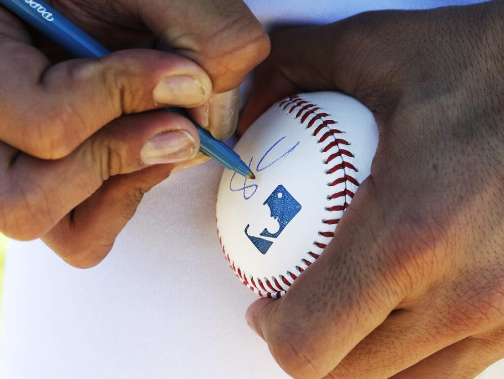 Los Angeles Dodgers' Sergio Romo signs a baseball during a spring training baseball workout Tuesday, Feb. 14, 2017, in Glendale, Ariz. (AP Photo/Morry Gash)