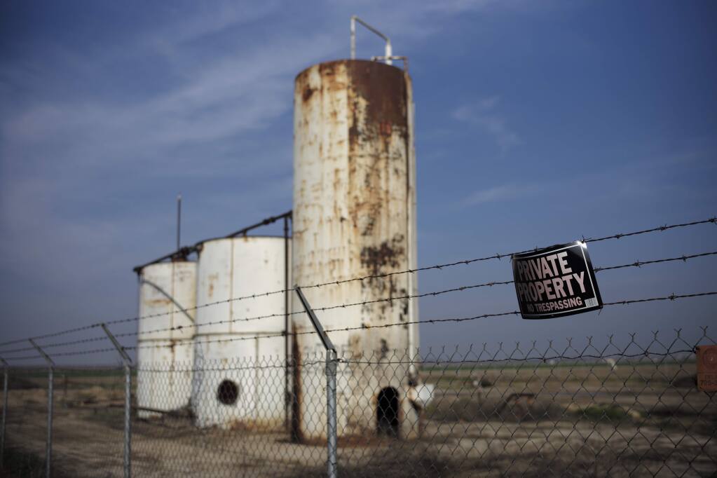 A private property sign hangs on the fence of a shut down injection well located next to an almond orchard owned by Palla Farms, Thursday, Jan. 15, 2015, in Bakersfield, Calif. Palla Farms filed suite blaming several oil companies for contaminating the local groundwater and killing cherry trees. (AP Photo/Jae C. Hong)