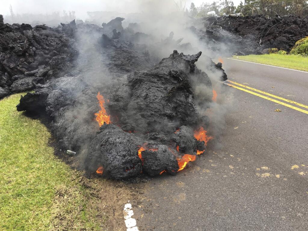Lava from the Kilauea volcano moves across the road in the Leilani Estates in Pahoa, Hawaii, Saturday, May 5, 2018. Hundreds of anxious residents on the Big Island of Hawaii hunkered down Saturday for what could be weeks or months of upheaval as the dangers from an erupting Kilauea volcano continued to grow. (AP Photo/Marco Garcia)