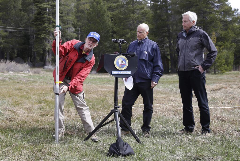Frank Gehrke, left, chief of the California Cooperative Snow Surveys Program for the Department of Water Resources, points to a mark on the snow pack measuring pole that was the lowest previous snow pack level as Gov. Jerry Brown, center and Mark Cowin, director of the Department of Water Resources look on at a news conference near Echo Summit, Calif., Wednesday, April 1, 2015. Gehrke said this was the first time since he has been conducting the survey at that he found no snow at this location at this time of the year. Brown took the occasion to announce that he signed an executive order requiring the state water board to implement measures in cities and towns to cut water usage by 25 percent compared with 2013 levels. (AP Photo/Rich Pedroncelli)