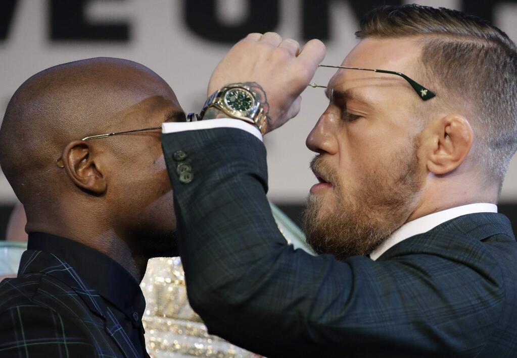 Conor McGregor, right, removes his glasses while posing for photographers with Floyd Mayweather Jr. during a news conference Wednesday, Aug. 23, 2017, in Las Vegas. The two are scheduled to fight in a boxing match Saturday in Las Vegas. (AP Photo/John Locher)