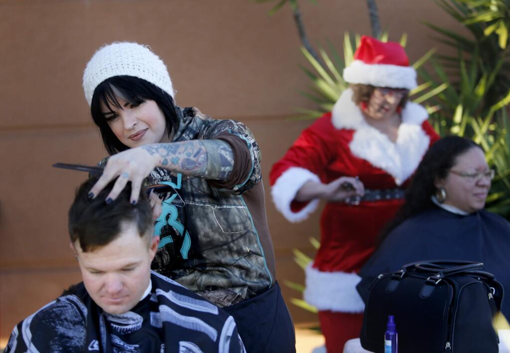 Hair dresser Danika O'Leary gives Trav Baker a trim while Teresa Madison cuts Tajmah Georges' hair during a resource fair for the homeless Sunday at the Palms Inn in Santa Rosa. (BETH SCHLANKER / The Press Democrat)