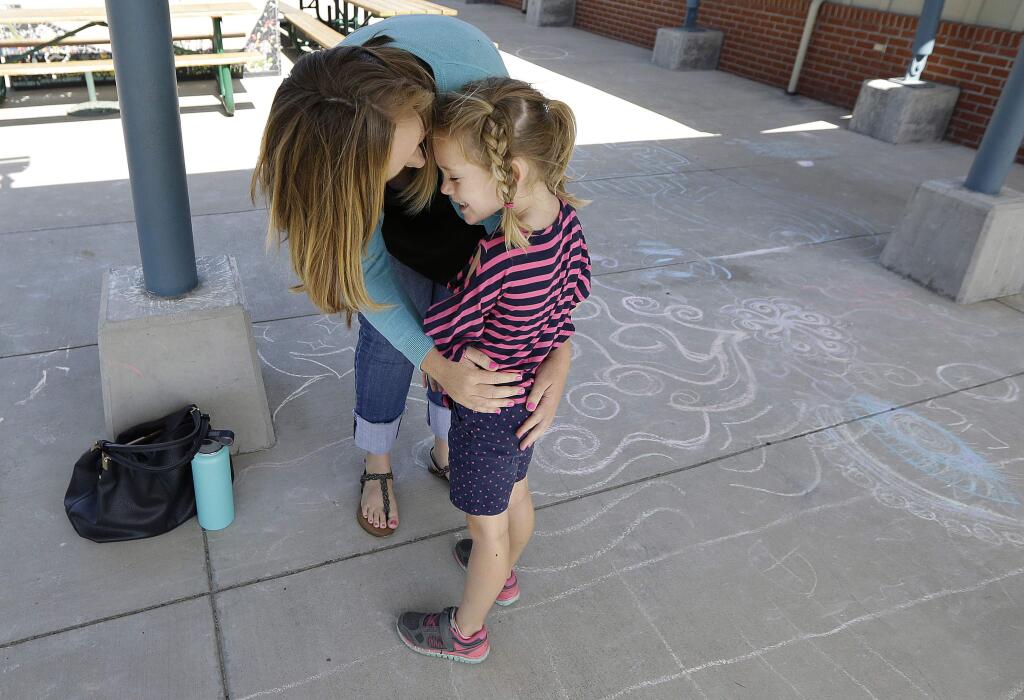 In this Tuesday, July 11, 2017 photo, Molly Maxwell hugs her child Gracie at the Bay Area Rainbow Day Camp in El Cerrito, Calif. The camp caters to transgender and 'gender fluid' children, aged 4-12, making it one of the only camps of its kind in the world open to preschoolers, experts say. (AP Photo/Jeff Chiu)