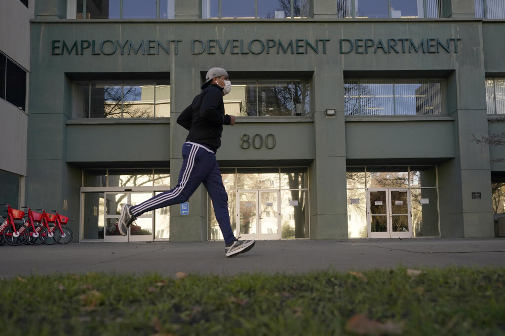 In his Dec. 18, 2020 file photo a runner passes the office of the California Employment Development Department in Sacramento, Calif. California reported a significant surge in unemployment claims last week for independent contractors, accounting for more than a quarter of all such climbs nationally and raising concerns about a return of widespread fraud, Thursday, Jan. 21, 2021. (AP Photo/Rich Pedroncelli, File)