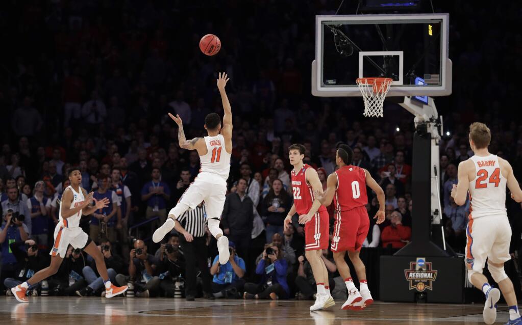 Florida guard Chris Chiozza (11) puts up a last second 3-point shot to score the game-winning points against Wisconsin in overtime of an East Region semifinal game of the NCAA tournament, Saturday, March 25, 2017, in New York. Florida won 84-83. (AP Photo/Julio Cortez)