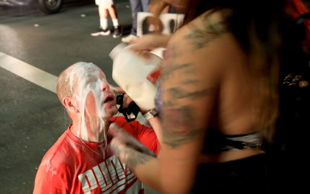 Milk is used to soften the sting after law enforcement officers fire tear gas to disperse a crowd at the downtown off-ramp in Santa Rosa on Saturday, May 30, 2020. (Kent Porter / The Press Democrat) 2020