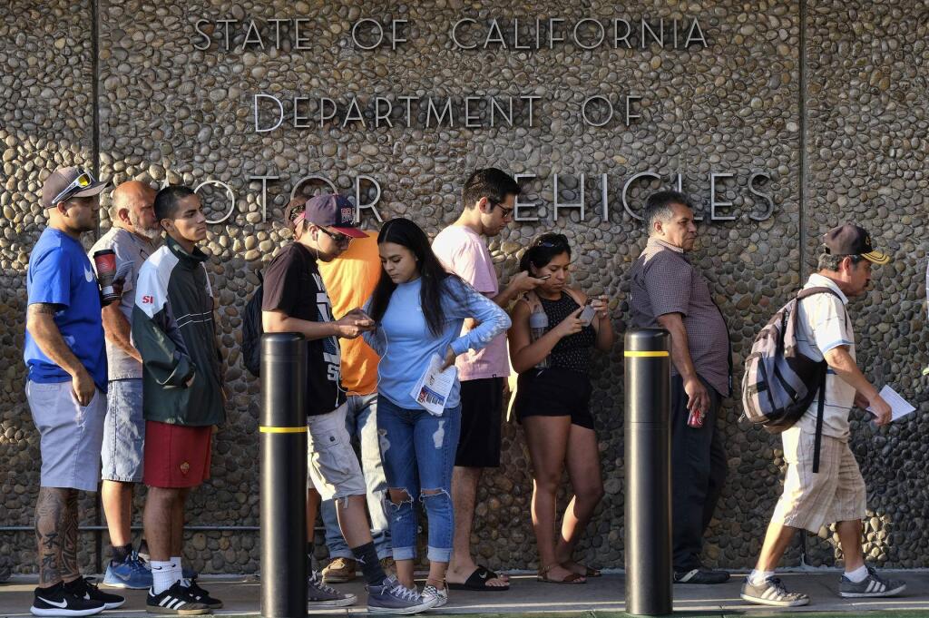 FILE - In this Aug. 7, 2018, file photo, people line up at the California Department of Motor Vehicles prior to opening in the Van Nuys section of Los Angeles. The California DMV's new voter registration program is confusing to voters and full of technical difficulties according to the findings of an audit released by the state Department of Finance, Friday, Aug. 9, 2019.(AP Photo/Richard Vogel, File)