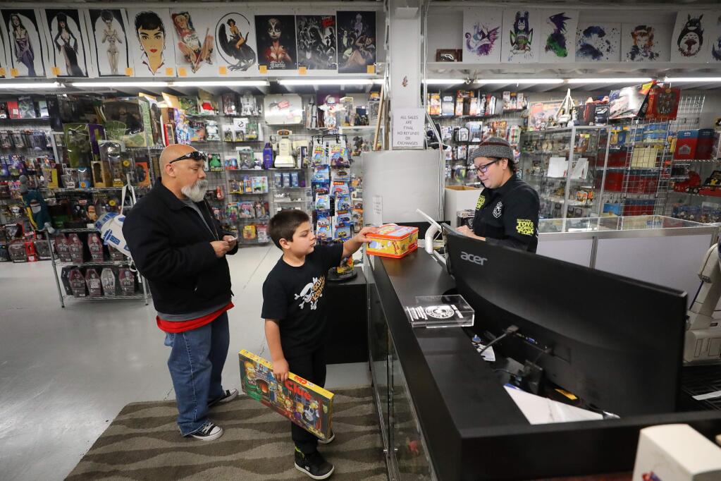 Bianca Wolfe, right, rings up Alex, 8, and Jesse Jacinto at The Batcave Comics & Toys, in Santa Rosa on Wednesday, February 5, 2020. (Christopher Chung/ The Press Democrat)